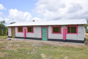 A white building with pink trim and green doors in Kenya.