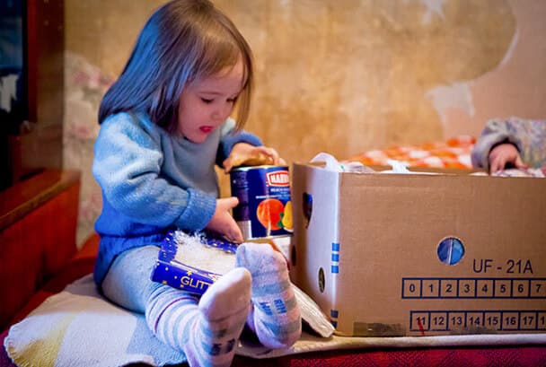 Liten flicka öppnar julpaket i Lettland