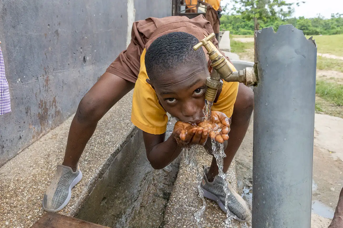 Barn dricker vatten från brunn i Ghana.