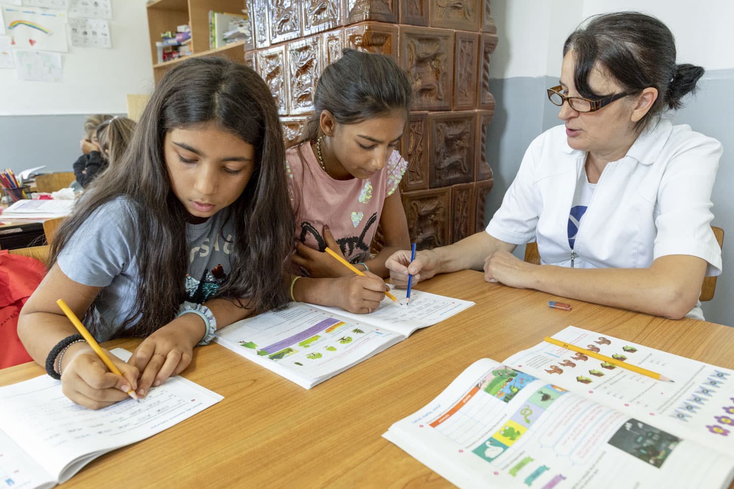 Två flickor får hjälp med läxor av lärare i Rumänien.