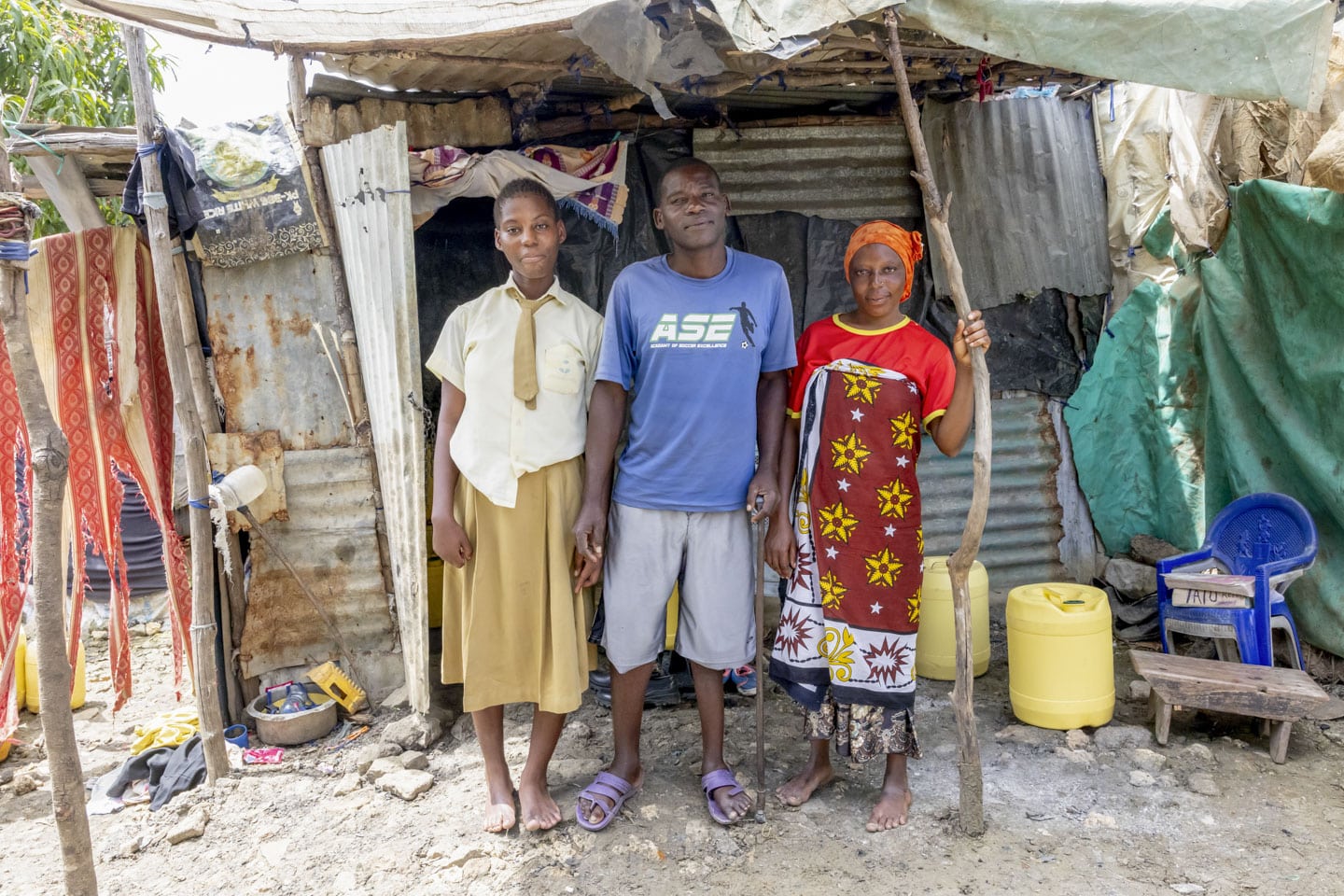 Flicka med föräldrar fram hus i slum i Kenya.