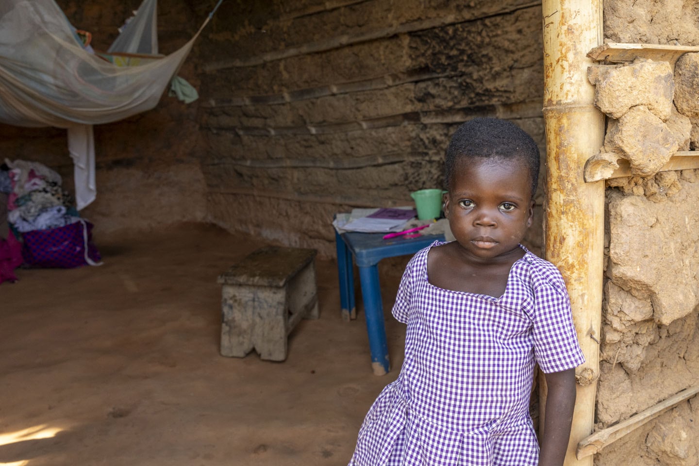 Flicka framför hus i Ghana. 