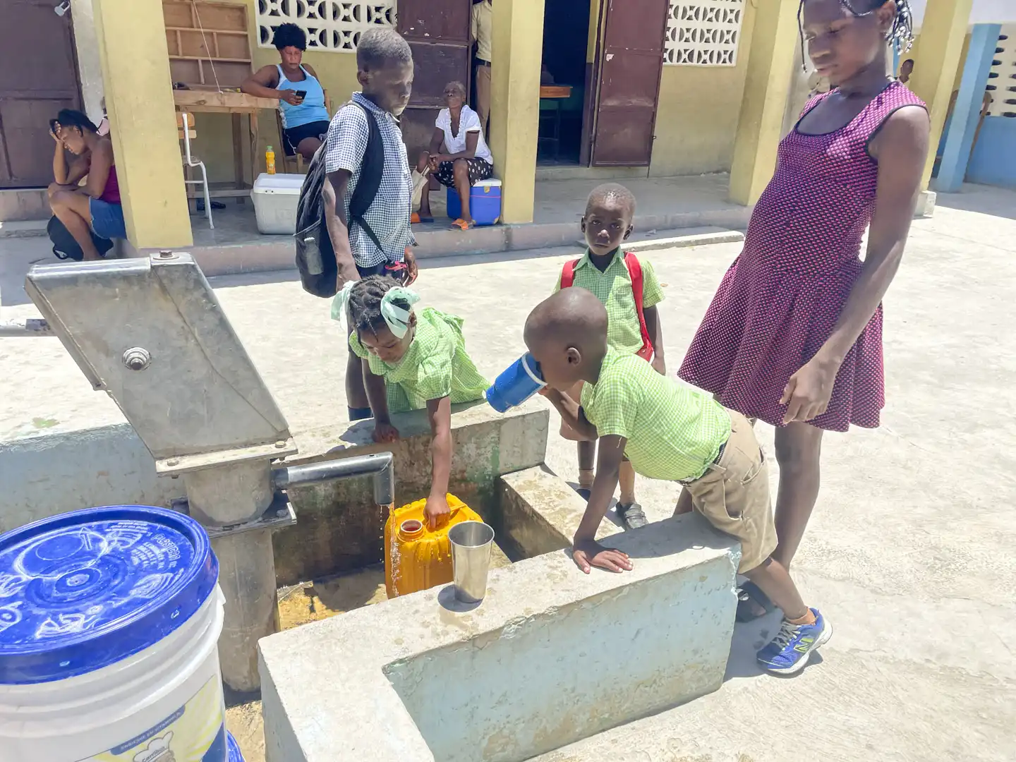 Barn dricker vatten på en skolgård i Haiti.