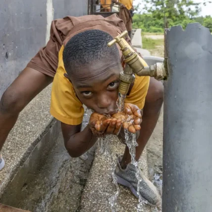 barn dricker vatten vid vattenbrunn i Ghana