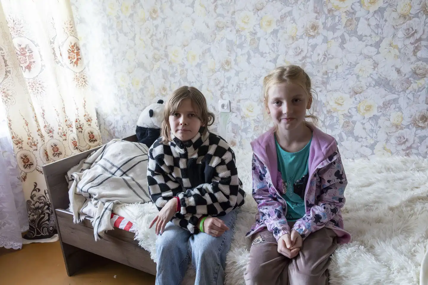 Två flickor sitter på en säng i Lettland.