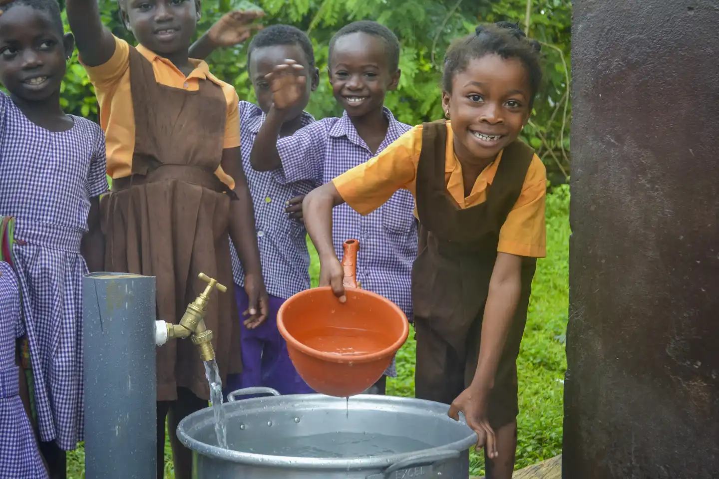 Barn öser vatten vid en skola i Ghana