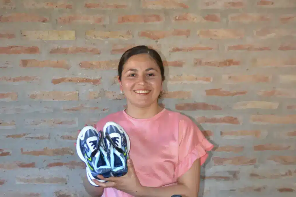 Från jordgolvet till drömjobbet 55 Kvinna i Argentina håller upp ett par skor.