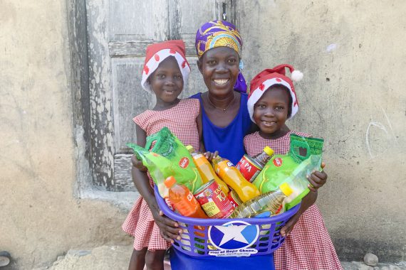 En mamma med två barn och julpaket i Ghana.
